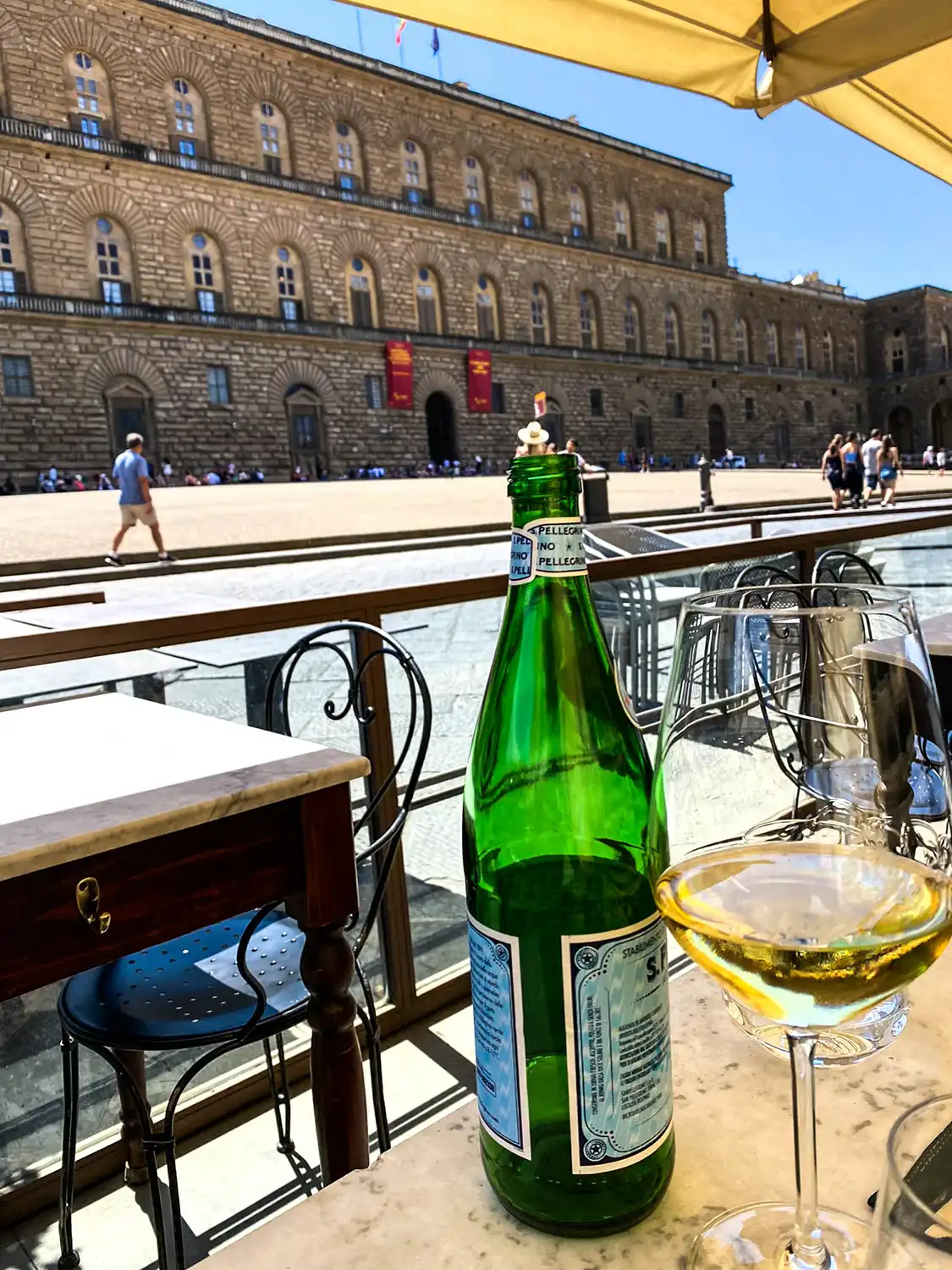 bottles of wine and glasses on a table outside a restaurant